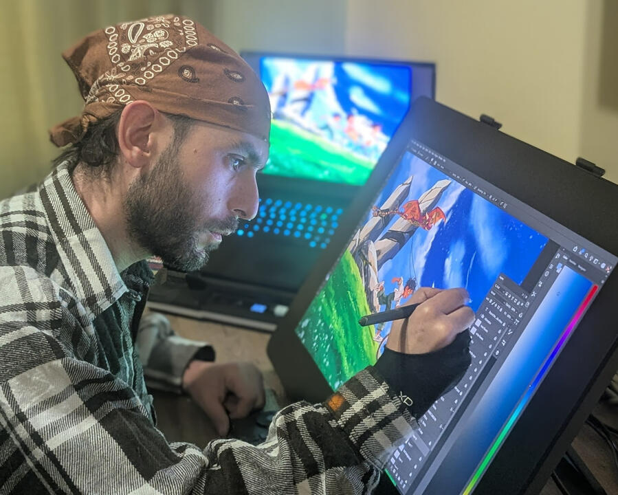 Children’s book illustrator Narek Saroyan working with a stylus on a digital drawing display, painting a colorful scene of children racing downhill with a dragon kite.